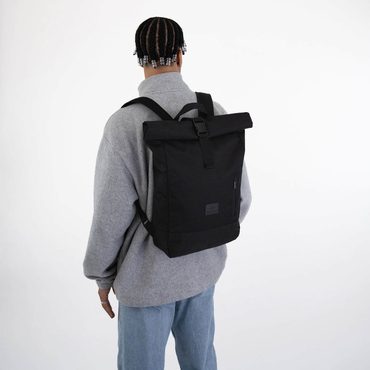 Person von hinten mit grauem Pullover und schwarzem Rolltop Rucksack ‚Robin Medium‘