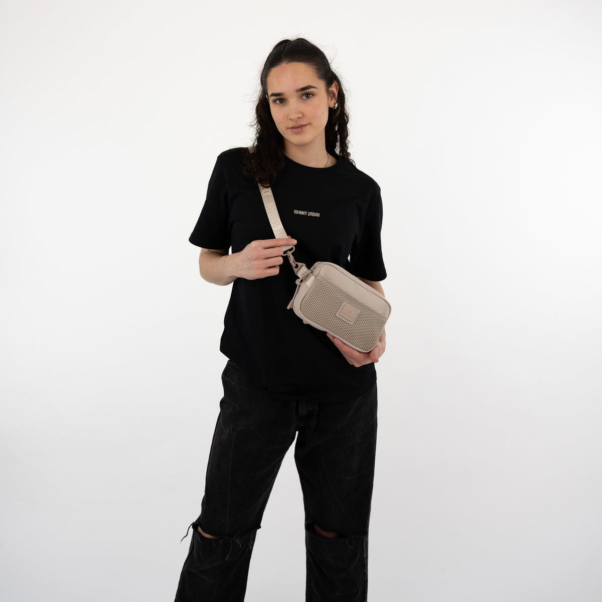 Frau trägt Umhängetasche 'Elliot' in Beige von Johnny Urban zur schwarzen T-Shirt und schwarzen Hose