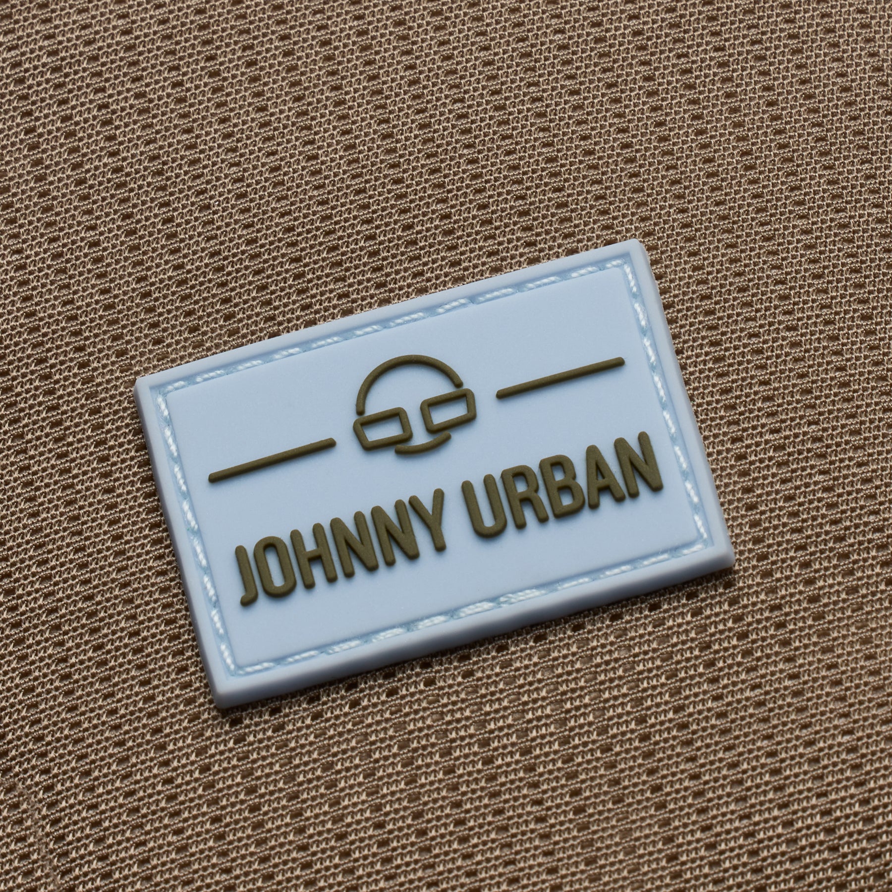 Nahe Aufnahme des Johnny Urban Logos auf einem braunen Stoff der Umhängetasche 'Lex'
