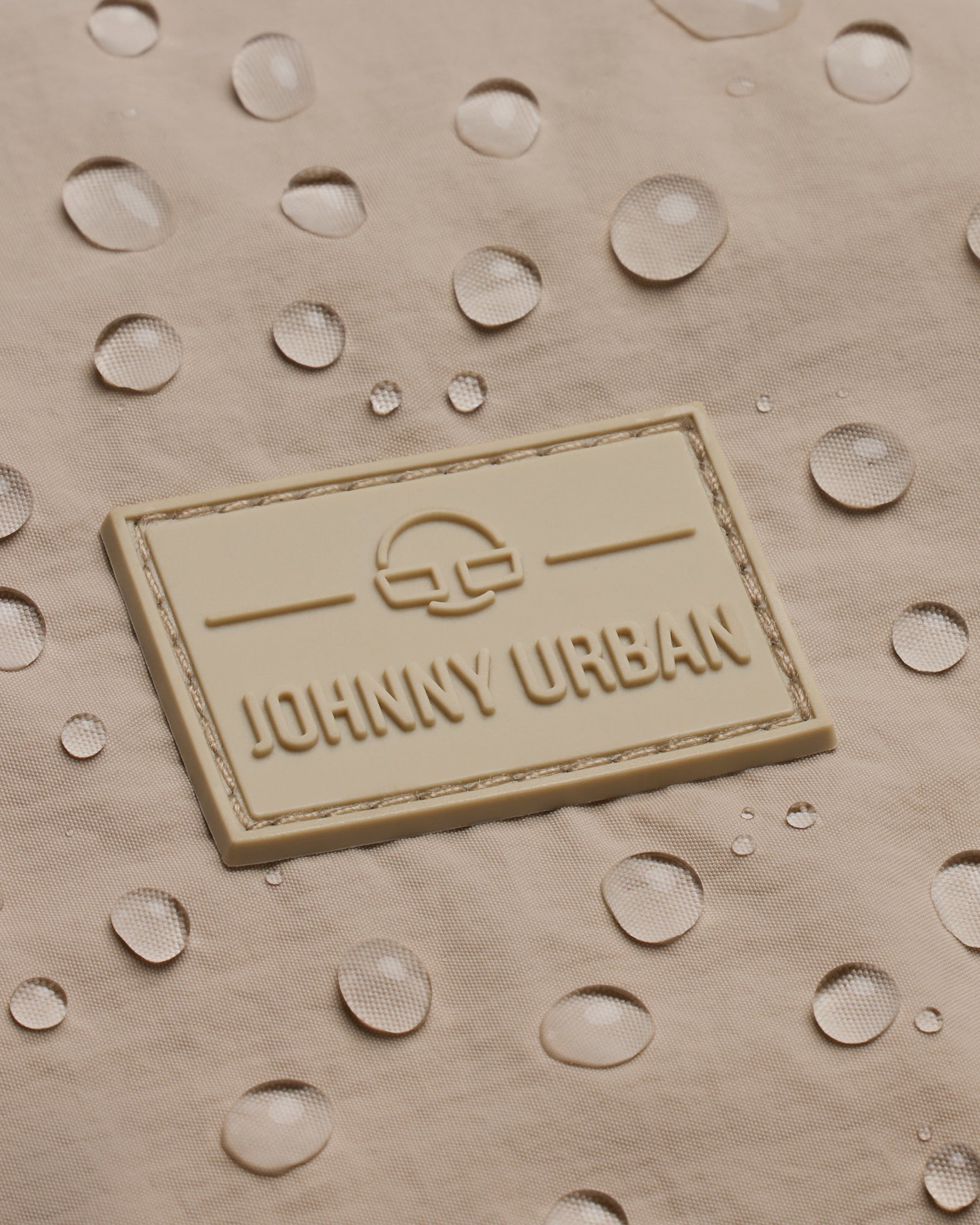 Wasserabweisendes beiges Material mit Johnny Urban Logo und Wassertröpfchen