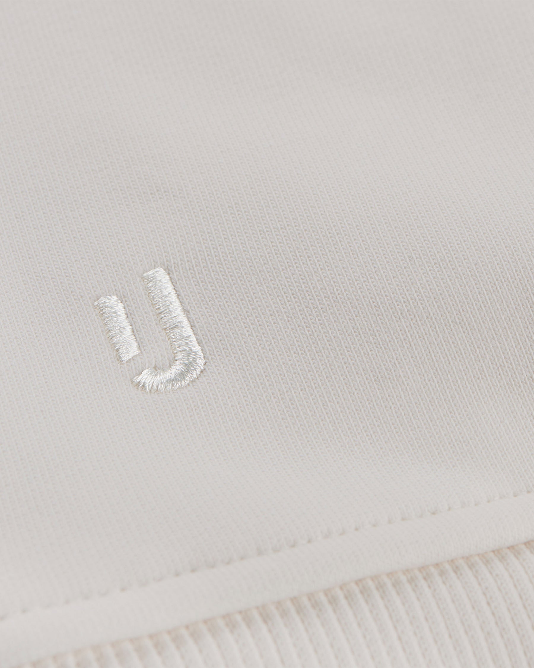 Nahe Ansicht des weißen gestickten Johnny-Urban-Logos auf cremeweißem Oversized Hoodie 'Cody'