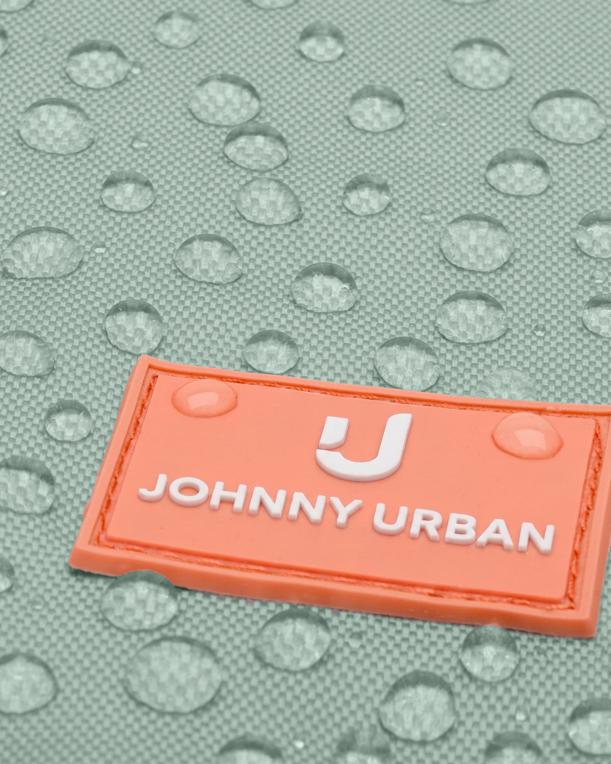 Nahaufnahme eines mintfarbenen Kinder-Turnbeutels mit orangefarbenem Johnny Urban Junior Logo und Wassertropfen