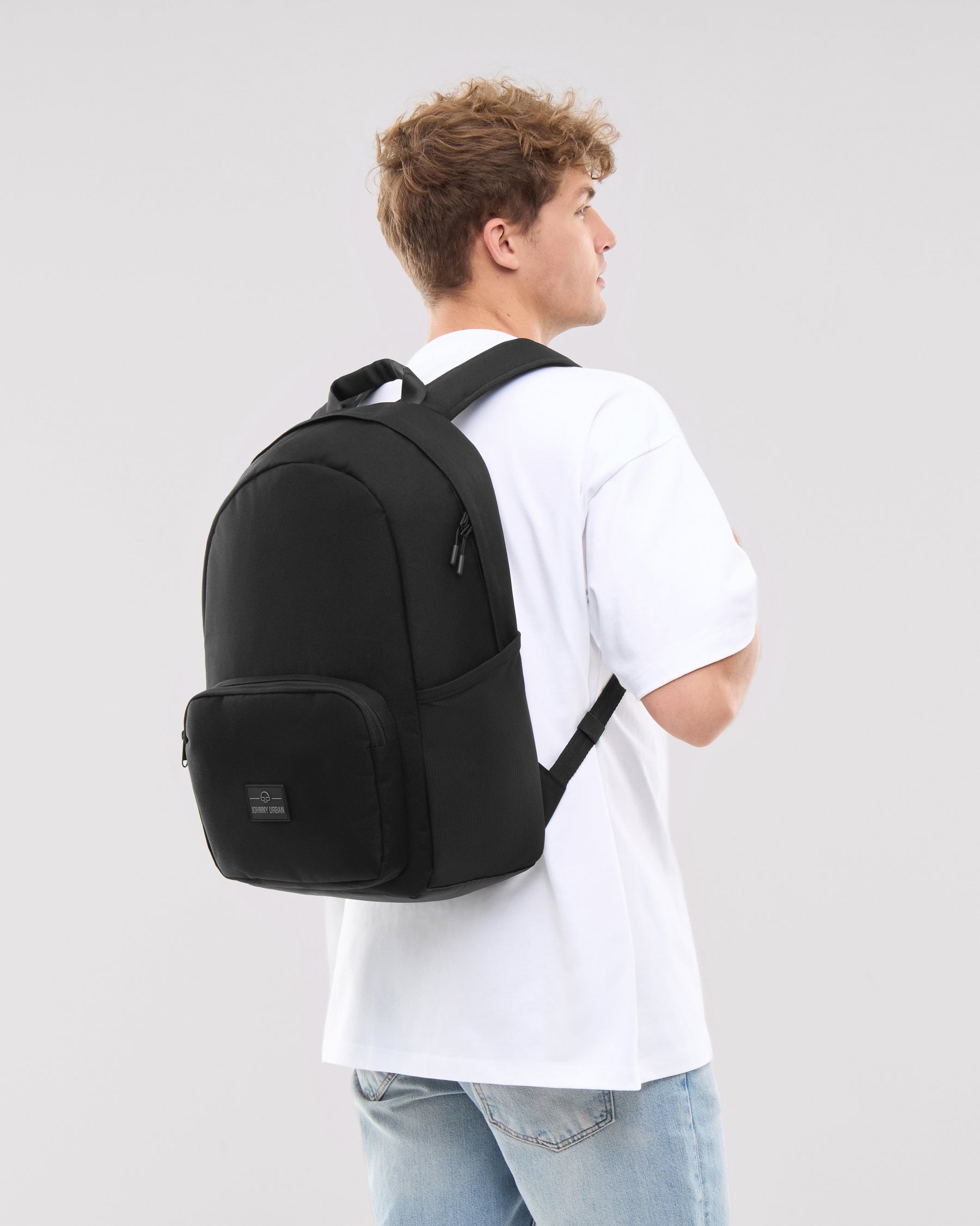 Mann trägt schwarzen Rucksack 'Mo' von Johnny Urban, weißes T-Shirt, Jeans