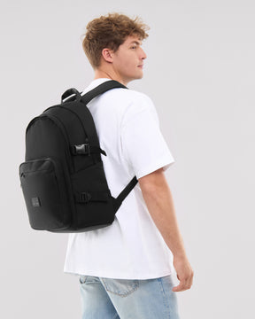 Mann trägt schwarzen Rucksack 'Lian' mit Fronttasche und Schnallen, weiße T-Shirt, blaue Jeans