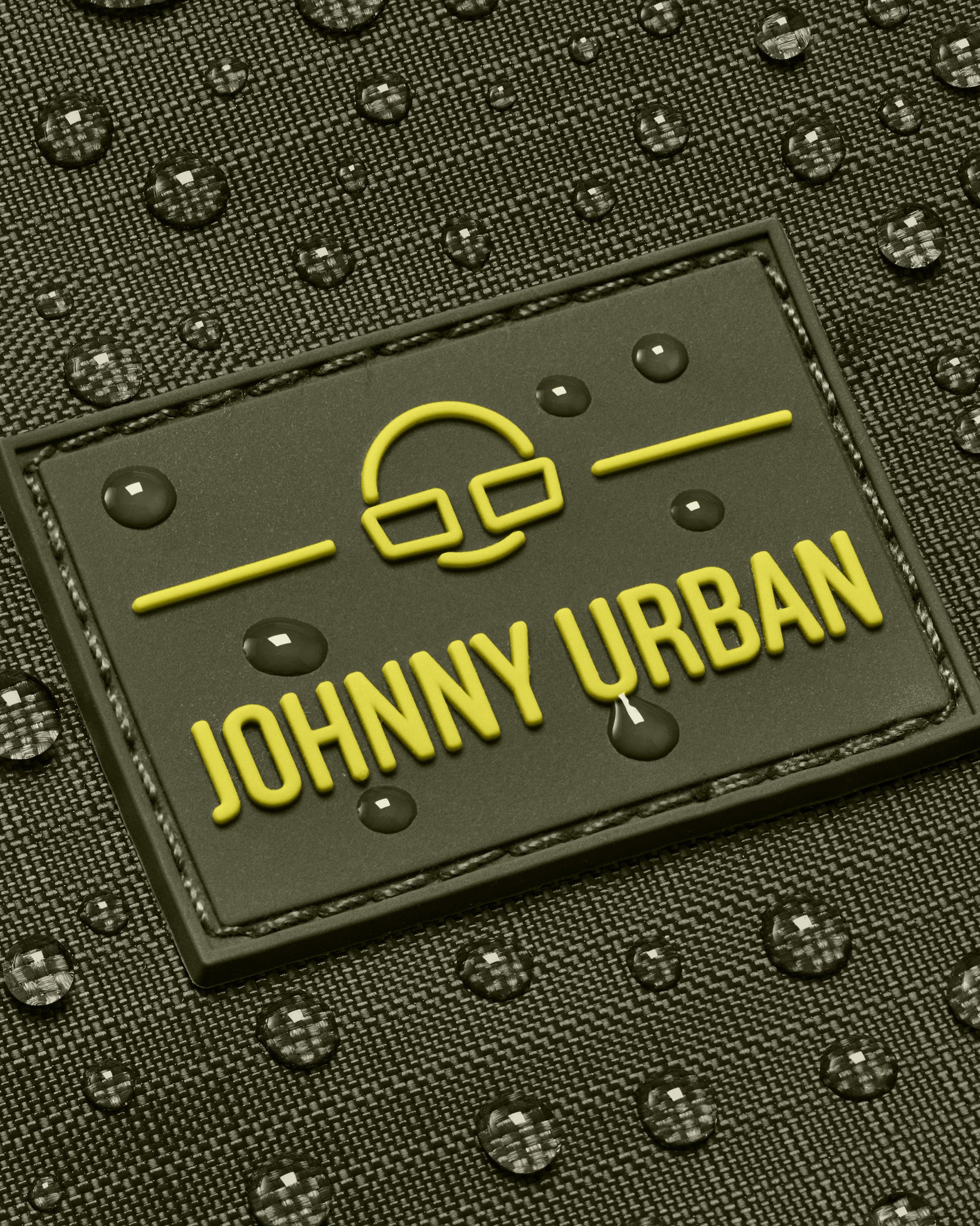 Nahaufnahme des Johnny Urban Logos auf einer olivfarbenen Duffle Bag "Shawn Medium" mit Wassertropfen