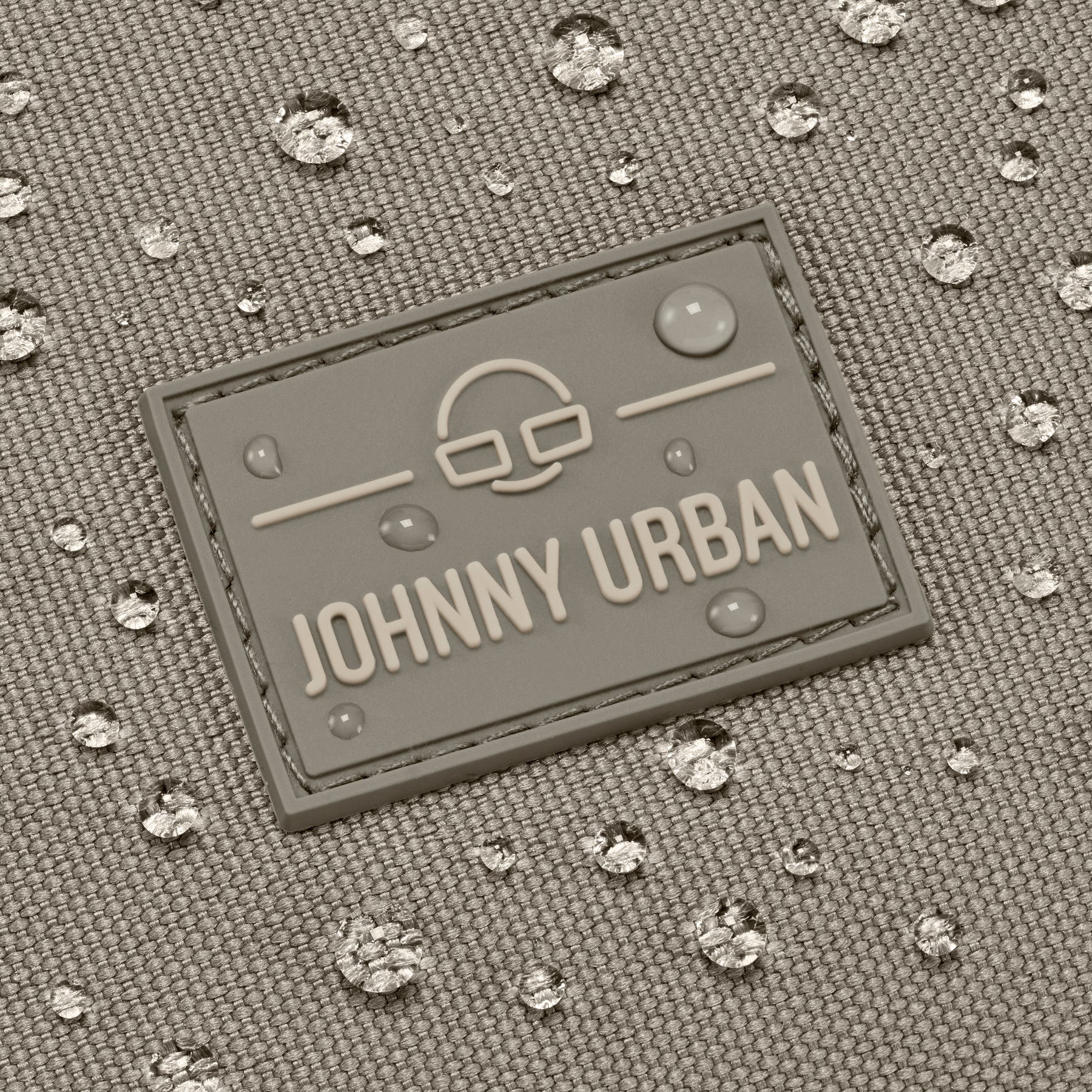 Nahe Aufnahme des wasserabweisenden Materials der Umhängetasche 'Drew' in Desert Grey mit Johnny Urban Logo