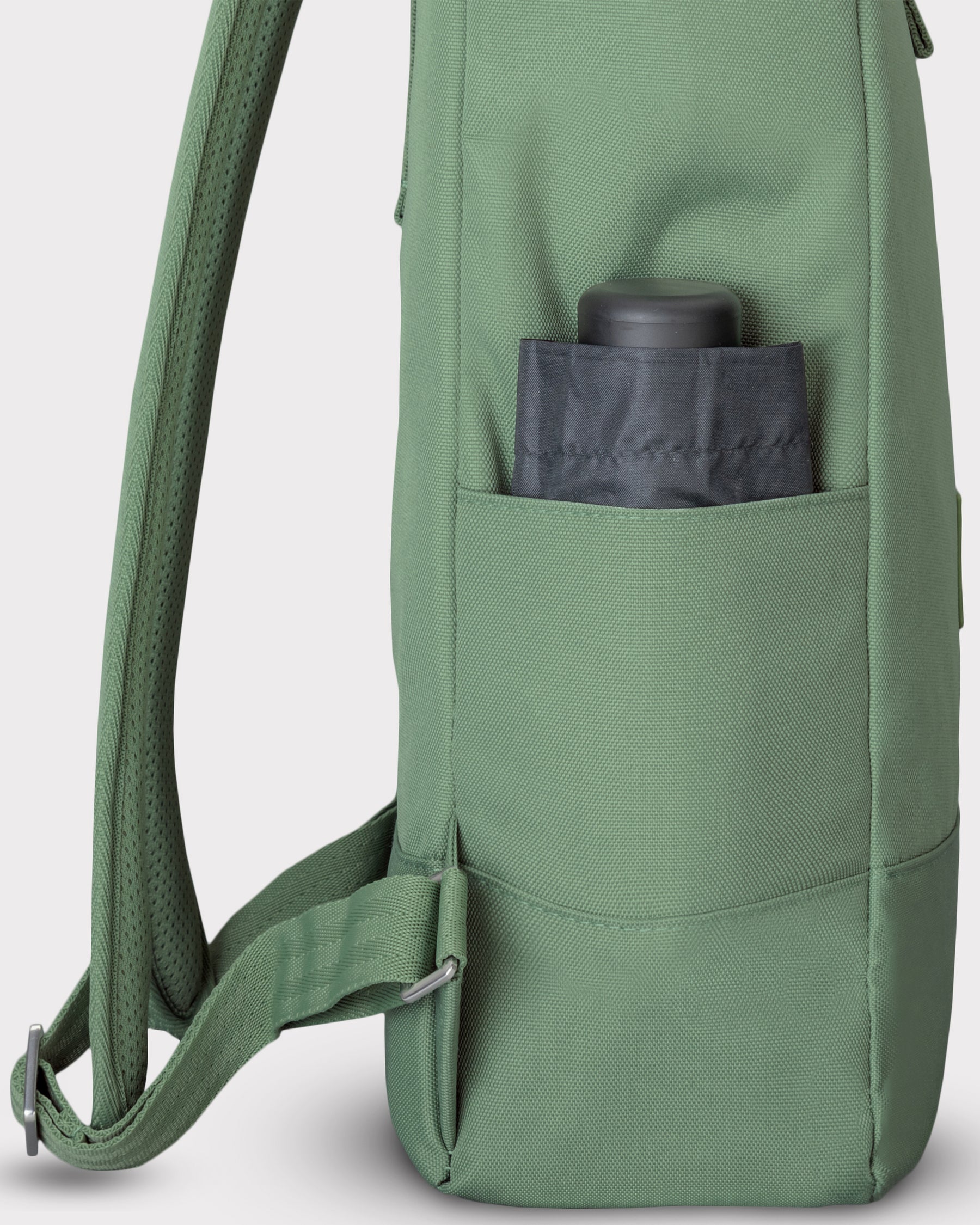 Grüner Rolltop-Rucksack 'Robin Medium' mit Seitentasche, darin ein schwarzer Gegenstand